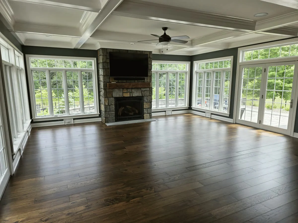 Four-season sunroom with coffered ceiling, stone fireplace and hardwood floors